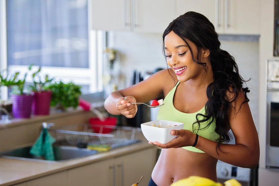 image of sportswoman eating cereal in kitchen