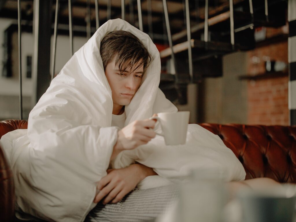 sick man drinking tea in a blanket